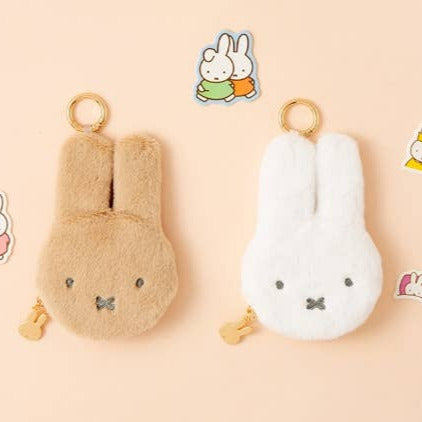 Two plush keychains shaped like rabbits on a beige background with small illustrations of the same design.