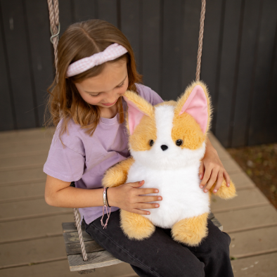 Child holding a plush dog toy on a wooden swing