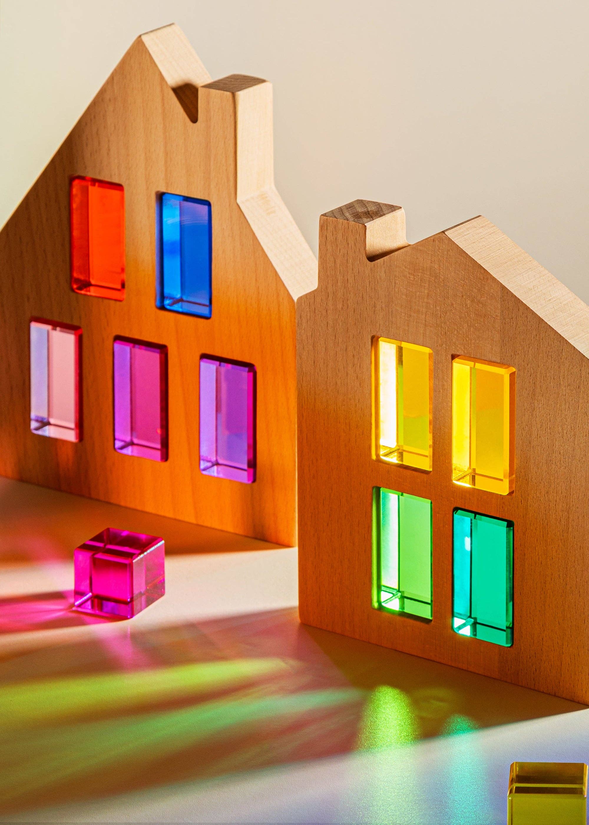 Wooden house model with colorful transparent windows on a neutral background