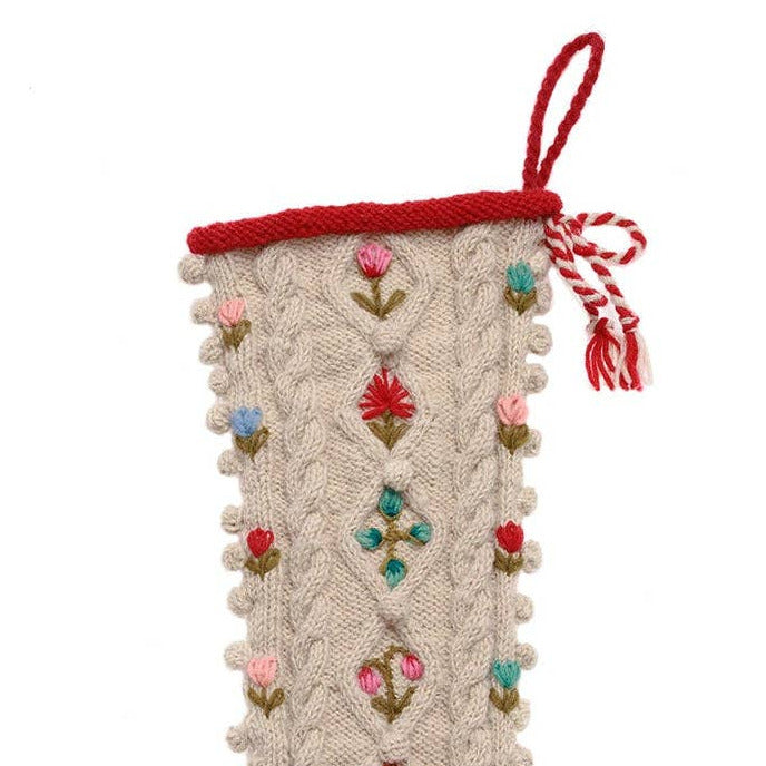 A festive Christmas stocking with a cream cable-knit body, decorated with colorful embroidered floral motifs, a red cuff, and a red toe. It features a hanging loop at the top and is shown against a plain white background.