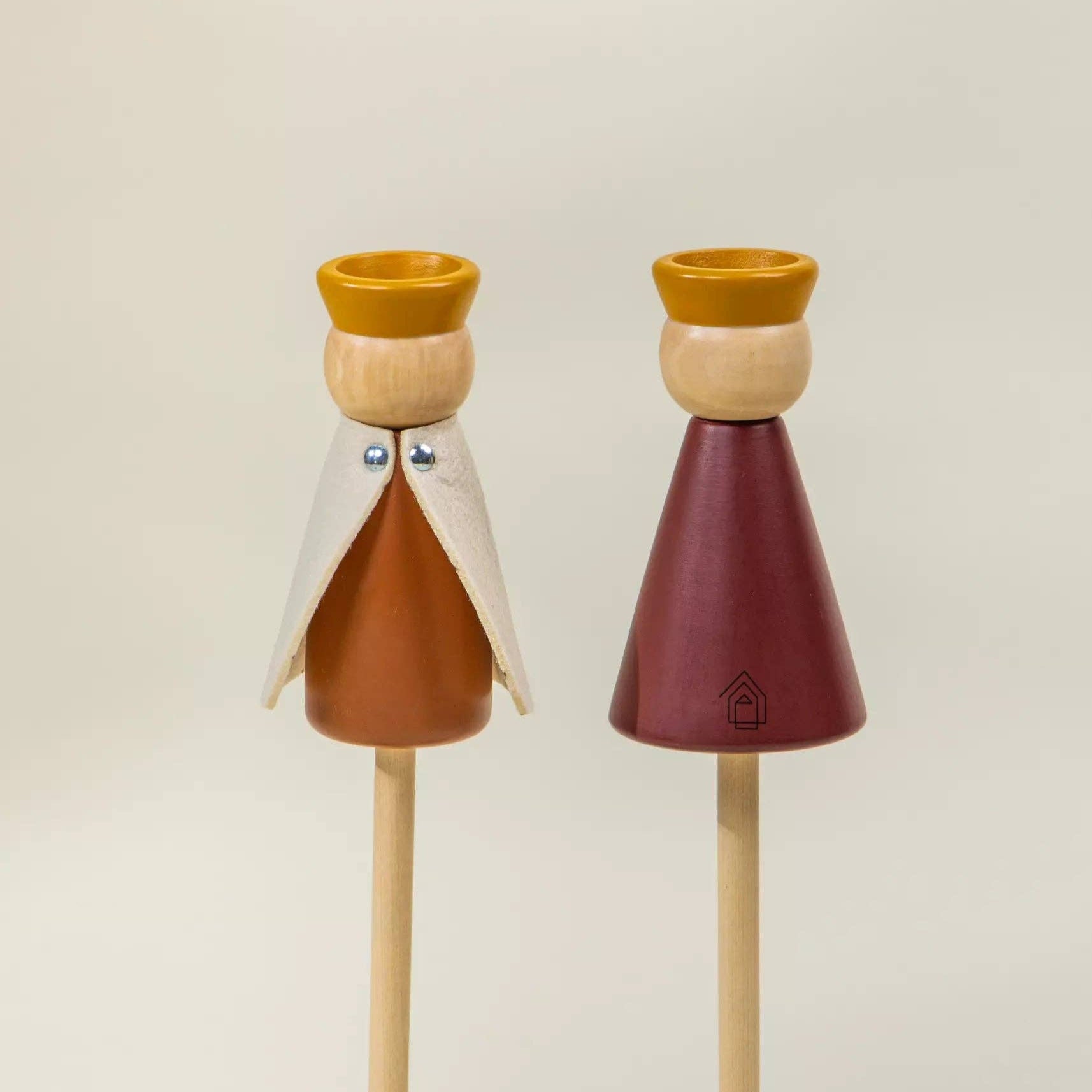 Two wooden figurines with colorful bodies and beards on a beige background