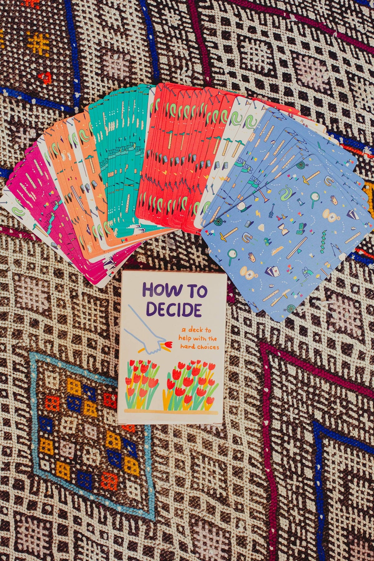 Colorful cards and a book titled 'How to Decide' on a patterned surface