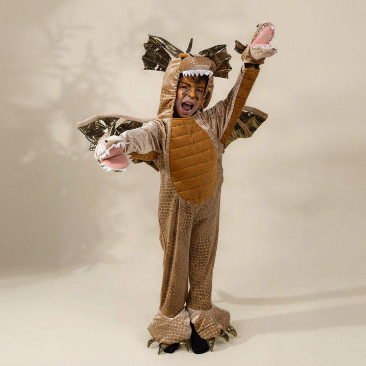 Child in a dragon costume with wings and a helmet on a plain background