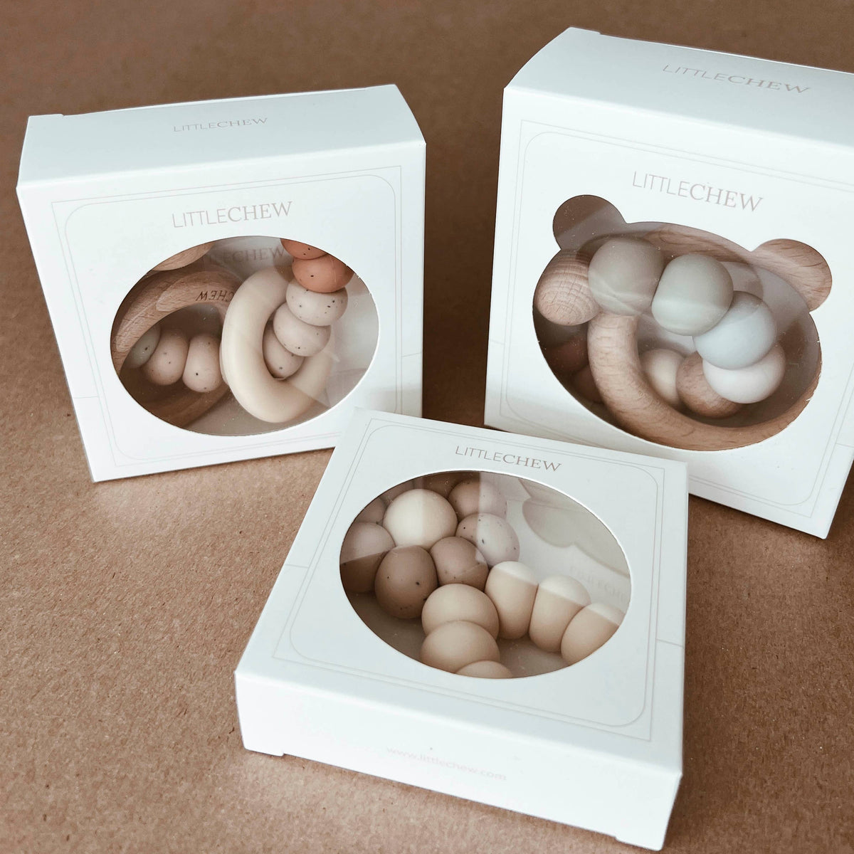 Three white boxes with transparent inserts containing round, beige objects on a brown background.