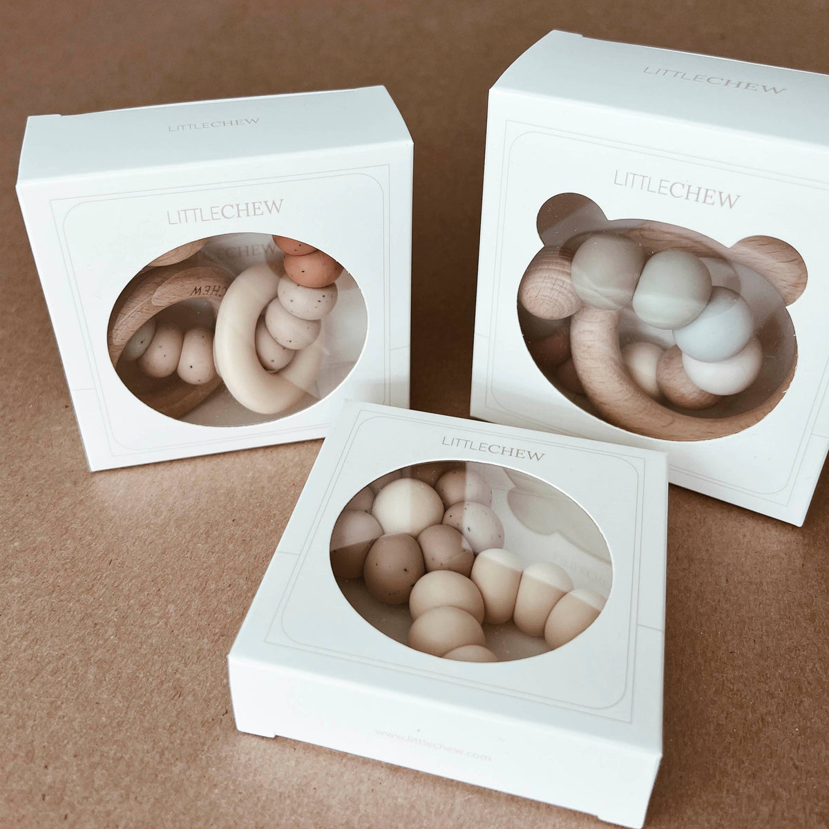 Three white boxes with transparent inserts containing round, beige objects on a brown background.