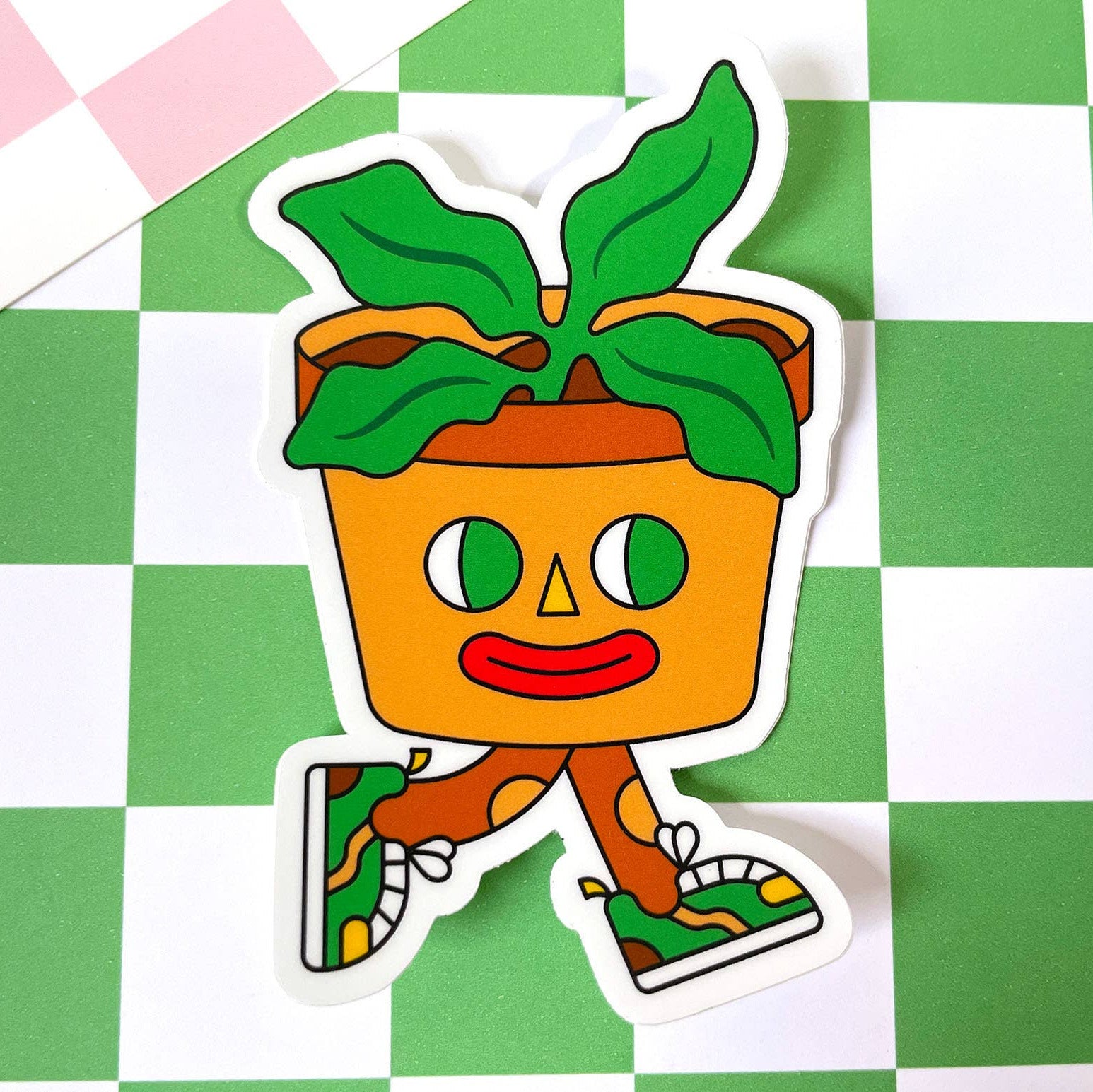 Cartoon potted plant sticker with a face on a green and white checkered background