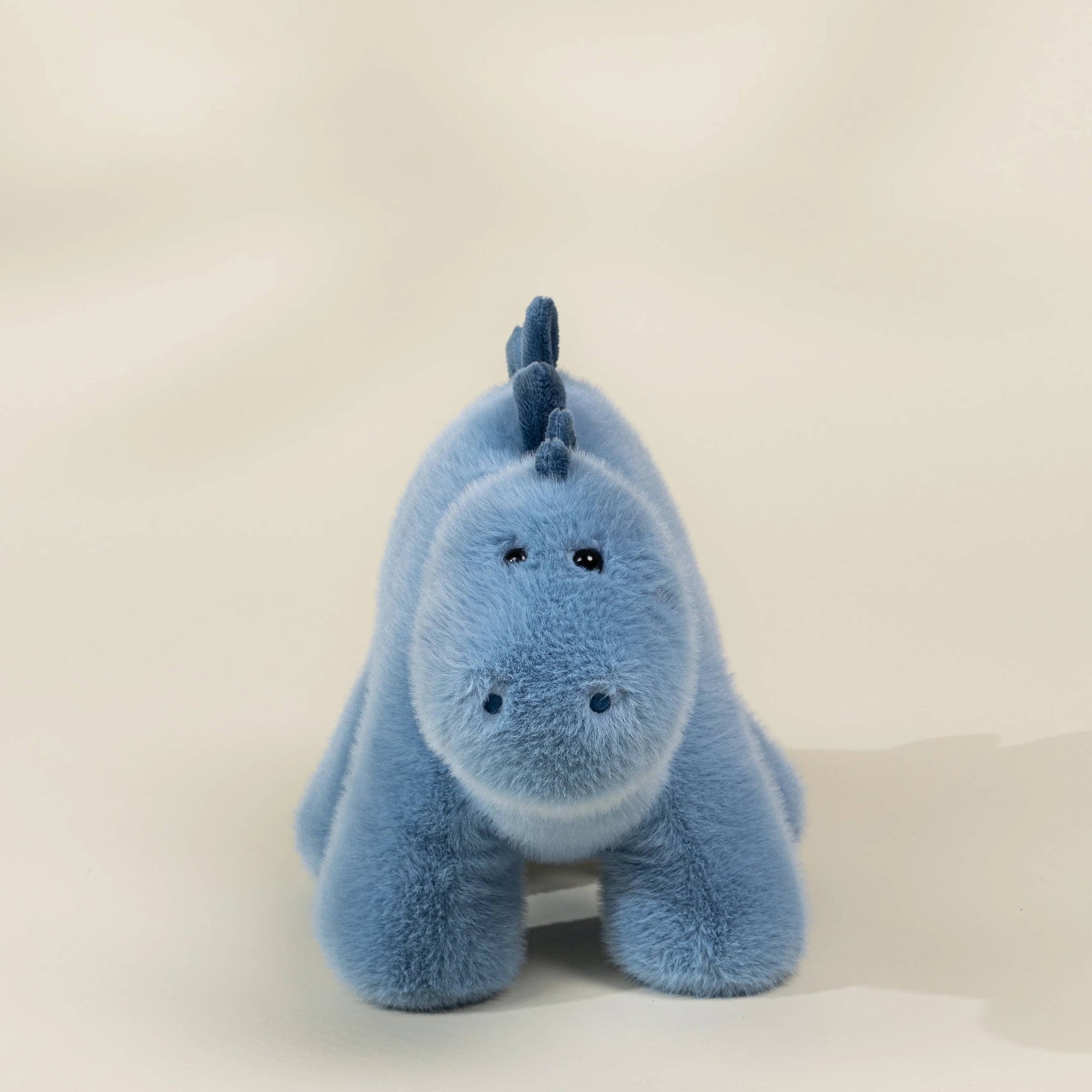 Blue plush toy with a unicorn design on a beige background