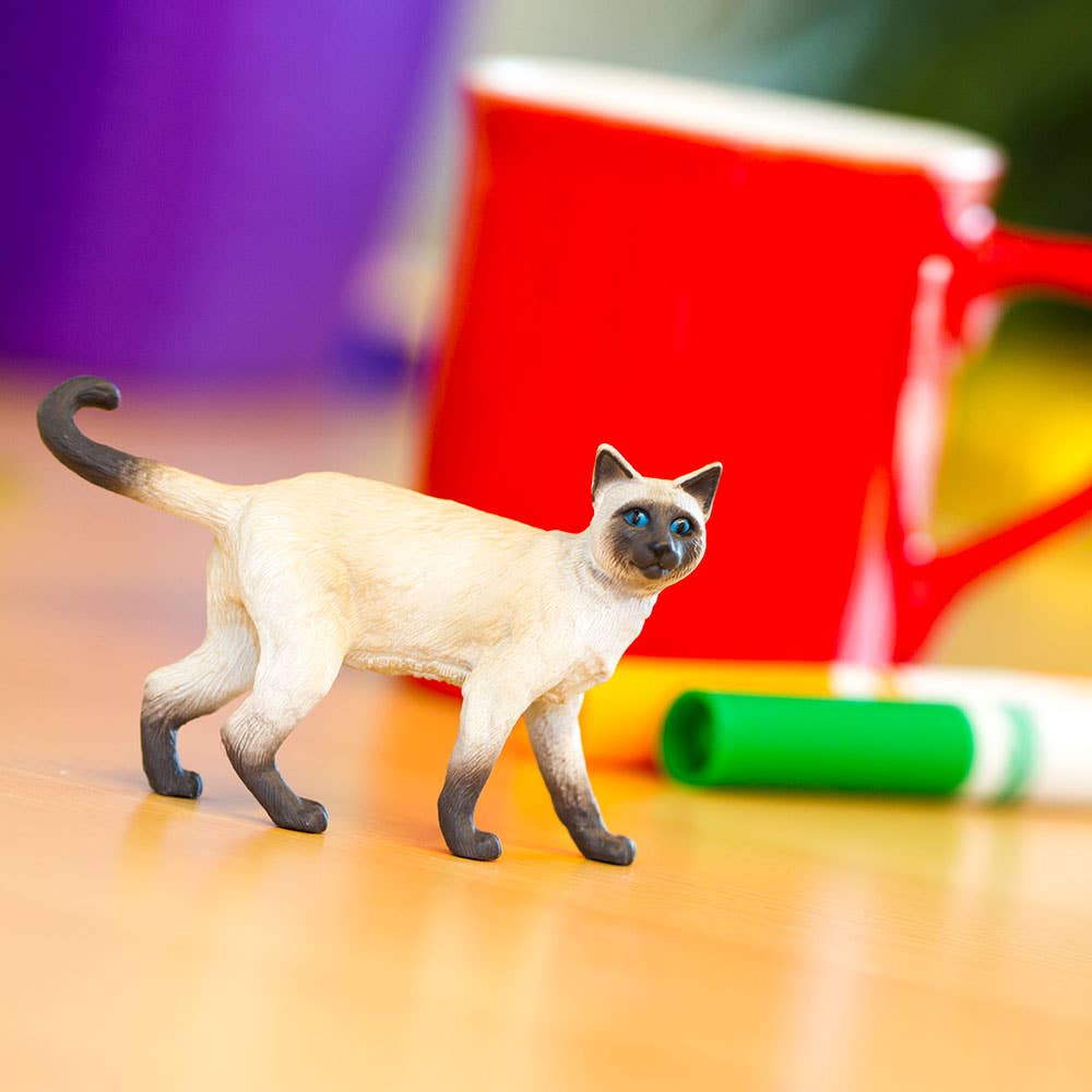 Toy cat figure on a colorful surface with markers in the background