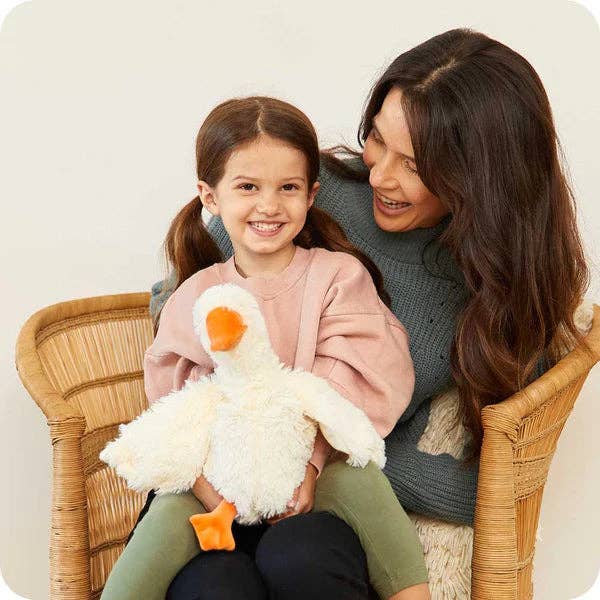 Woman and child sitting together holding a plush duck toy in a wicker chair.