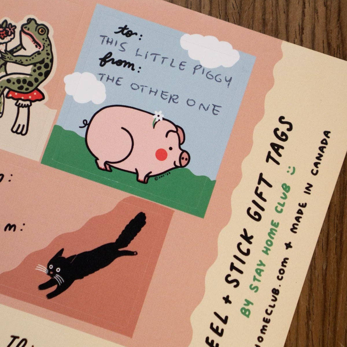 Packaging of peel and stick gift tags with cartoon illustrations on a wooden surface