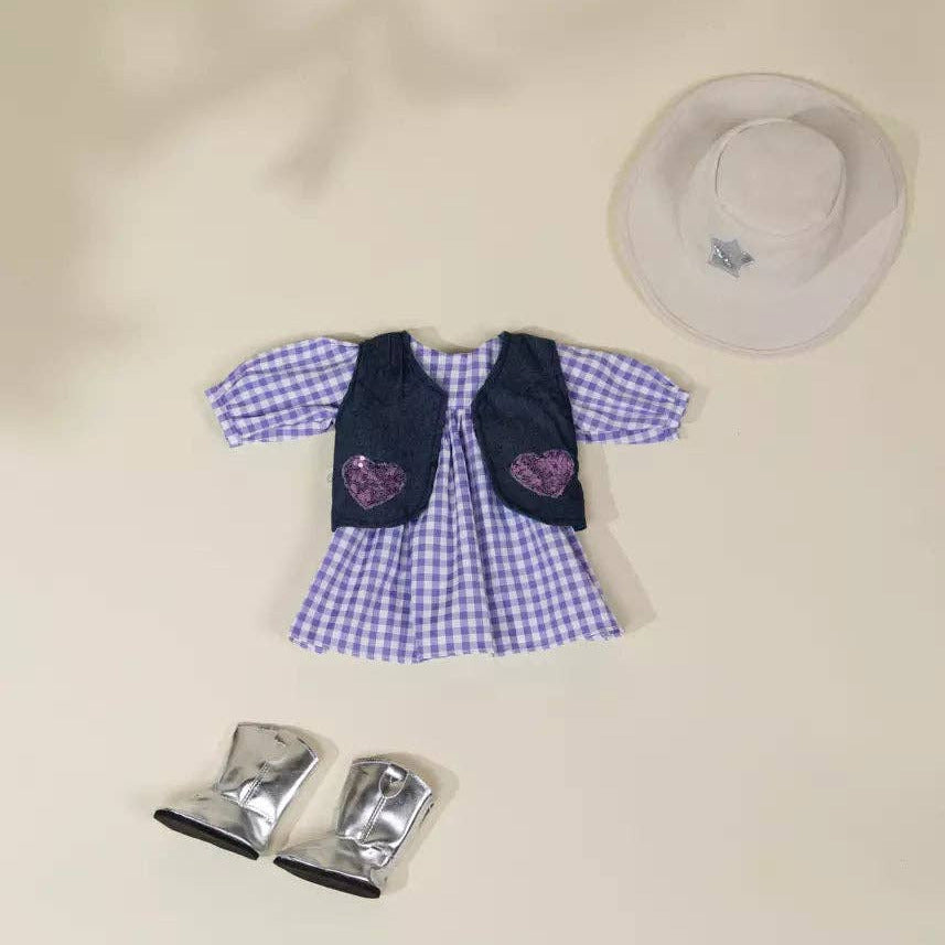 A doll outfit set featuring a blue and white gingham dress with a navy vest, purple heart patches, silver boots, and a white sun hat, arranged on a beige background.