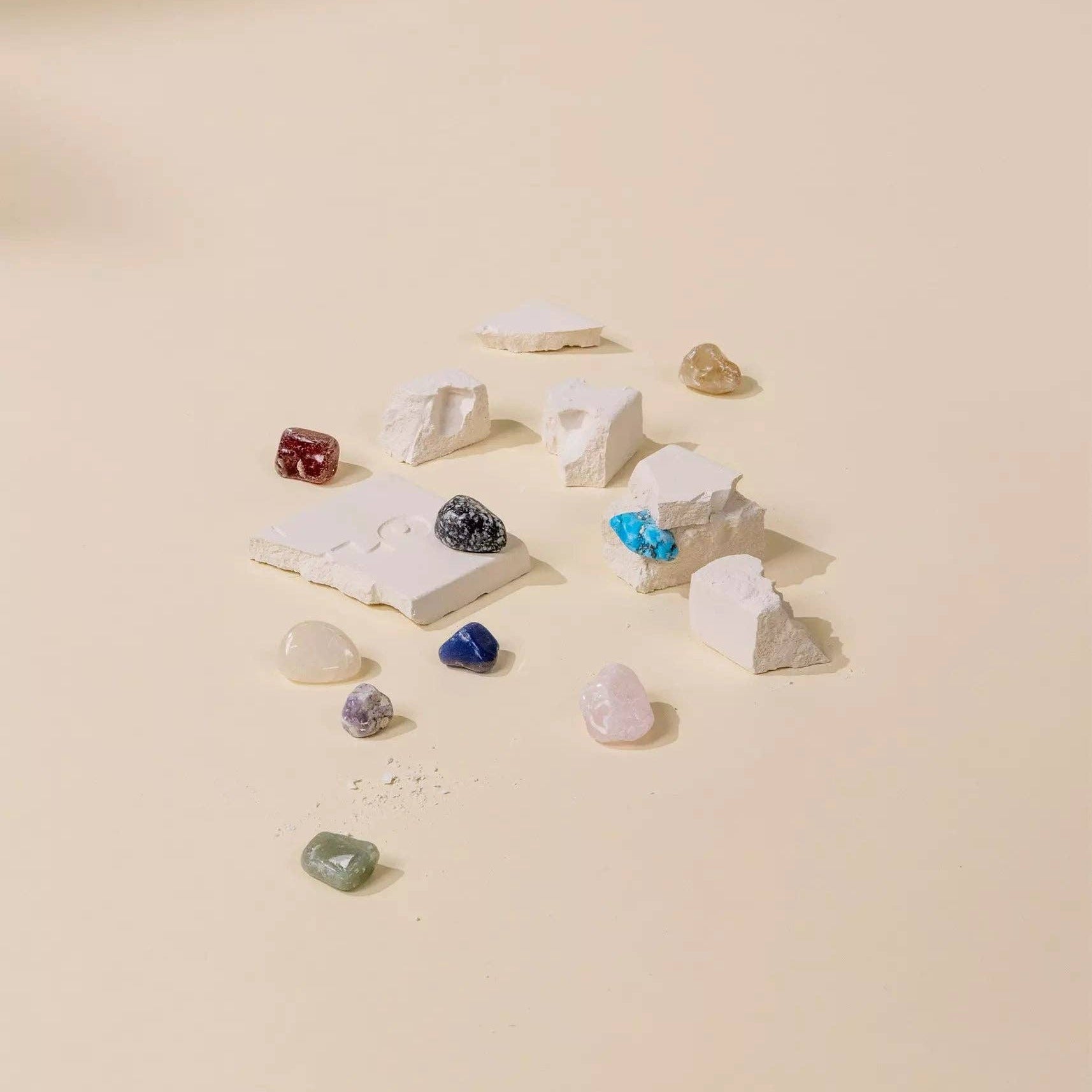 Collection of gemstones and jewelry on a beige surface