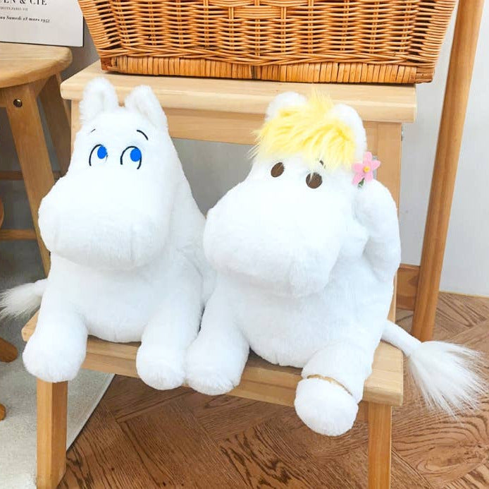 Two plush toys resembling white creatures with blue and yellow hair on a wooden chair.