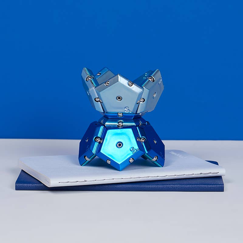 Metallic blue geometric object on a white surface with a blue background