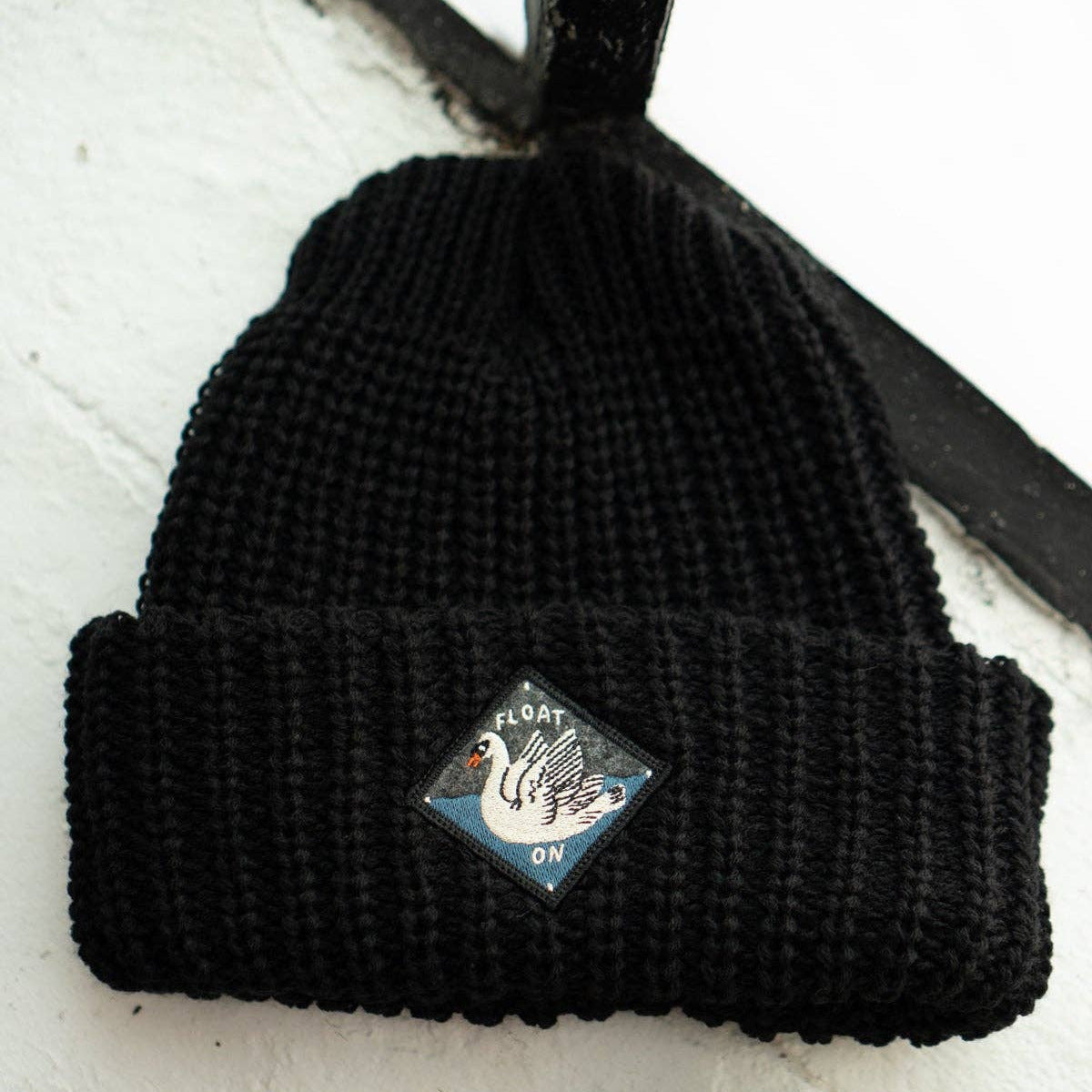 Black beanie with a logo on a white surface 