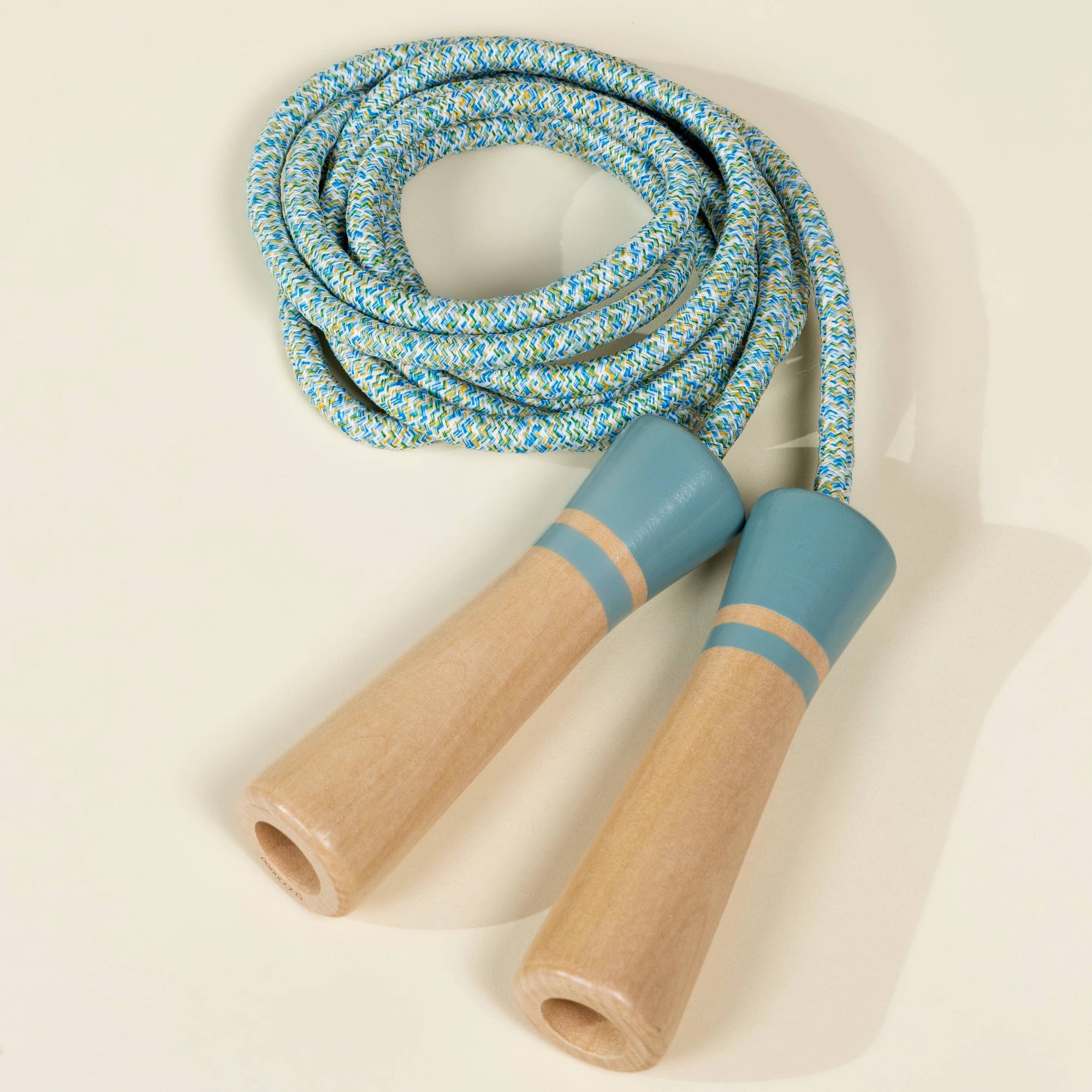 Skip rope with blue and beige handles on a beige background