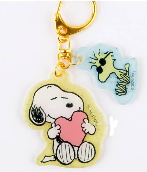 Keychain with a cartoon character holding a heart, with a smaller character in the background on a white background.