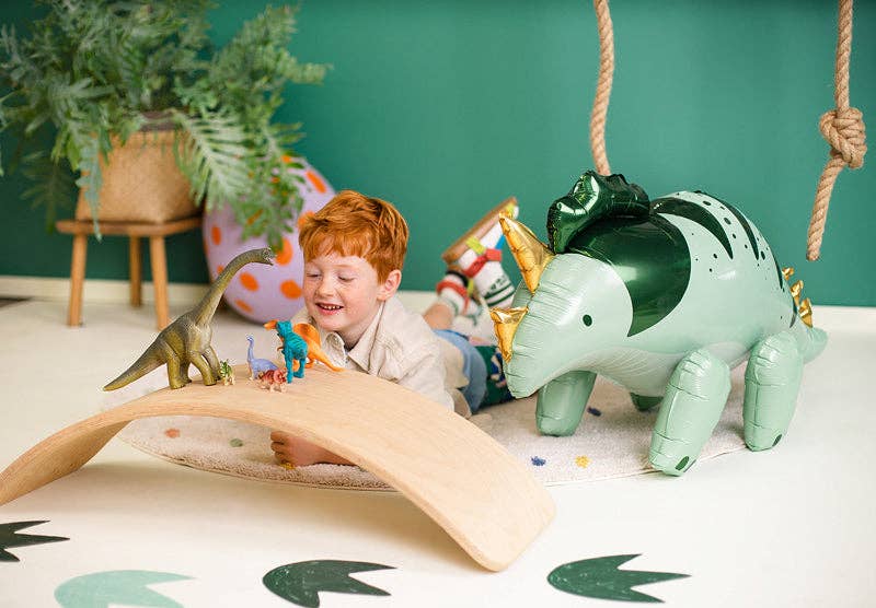 Child playing with dinosaur toys in a room with green walls and plants.