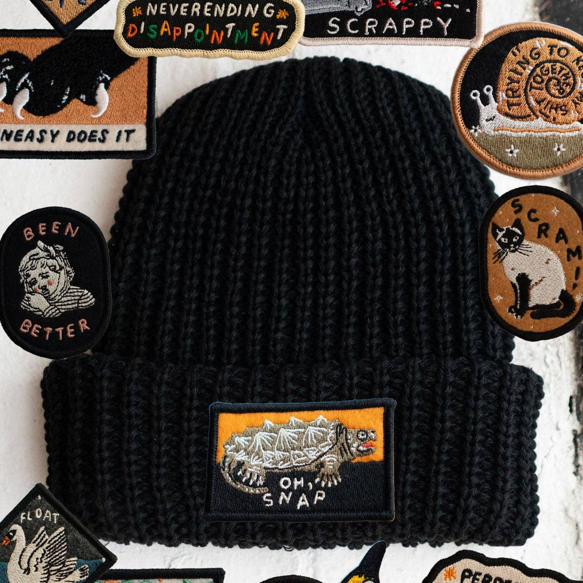Black beanie with various patches on a textured background