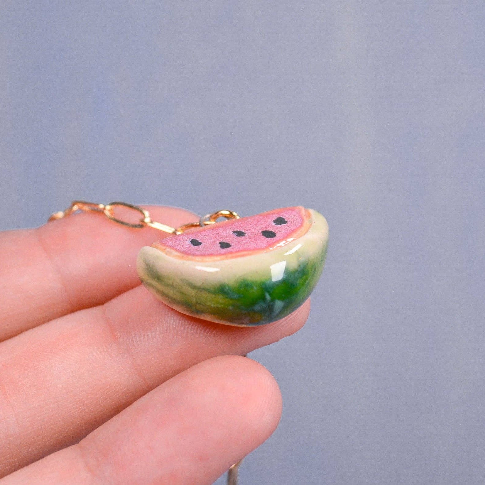 Watermelon slice keychain held in a hand against a plain background