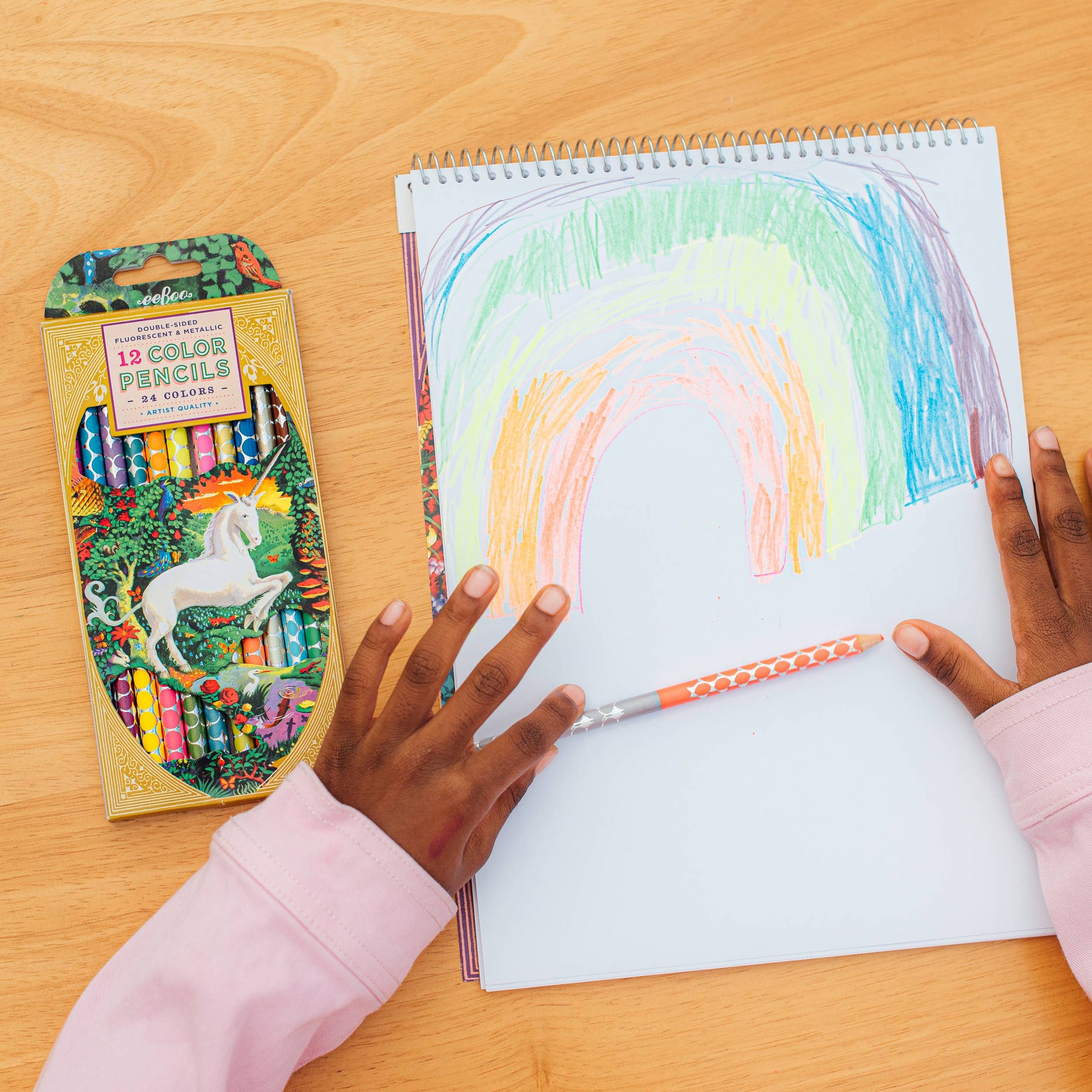 Coloring book with a rainbow design and color pencils on a wooden table