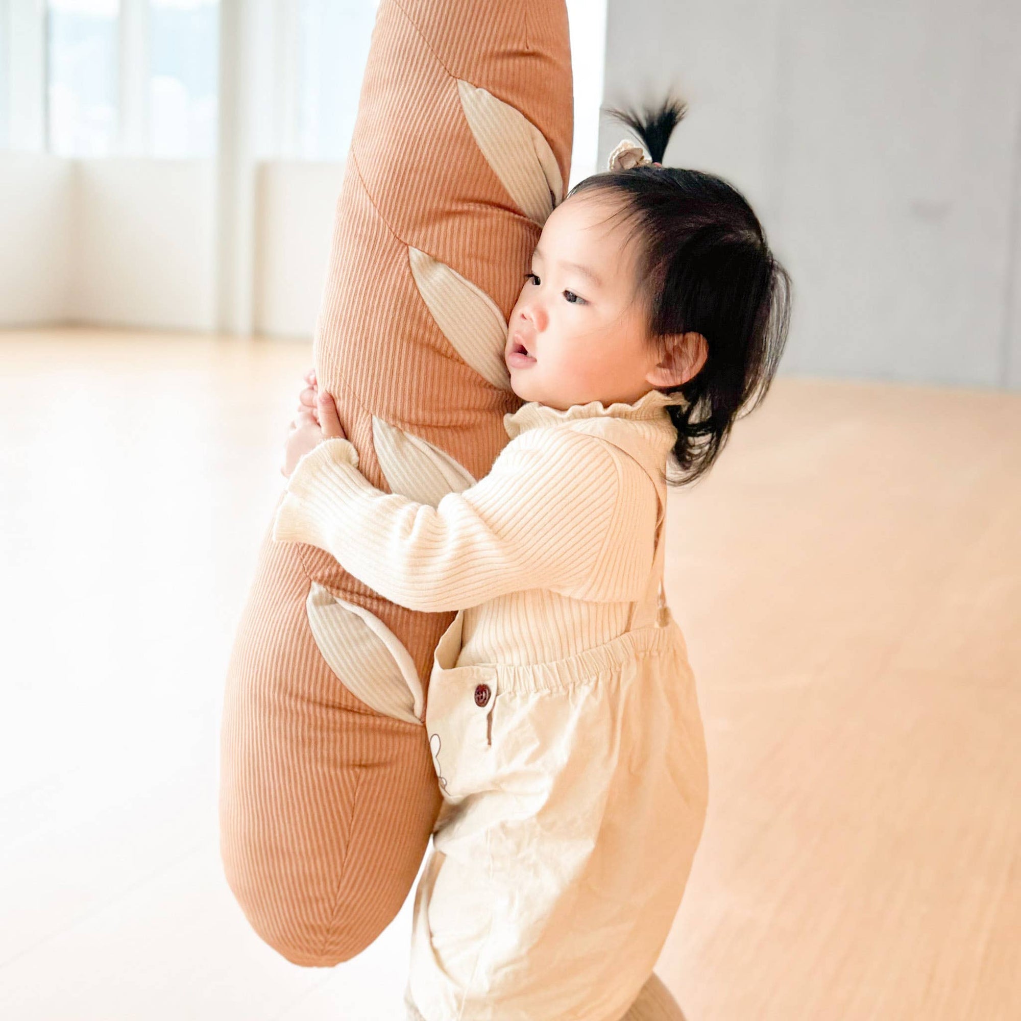 Child in a bunny costume standing on a person's leg indoors