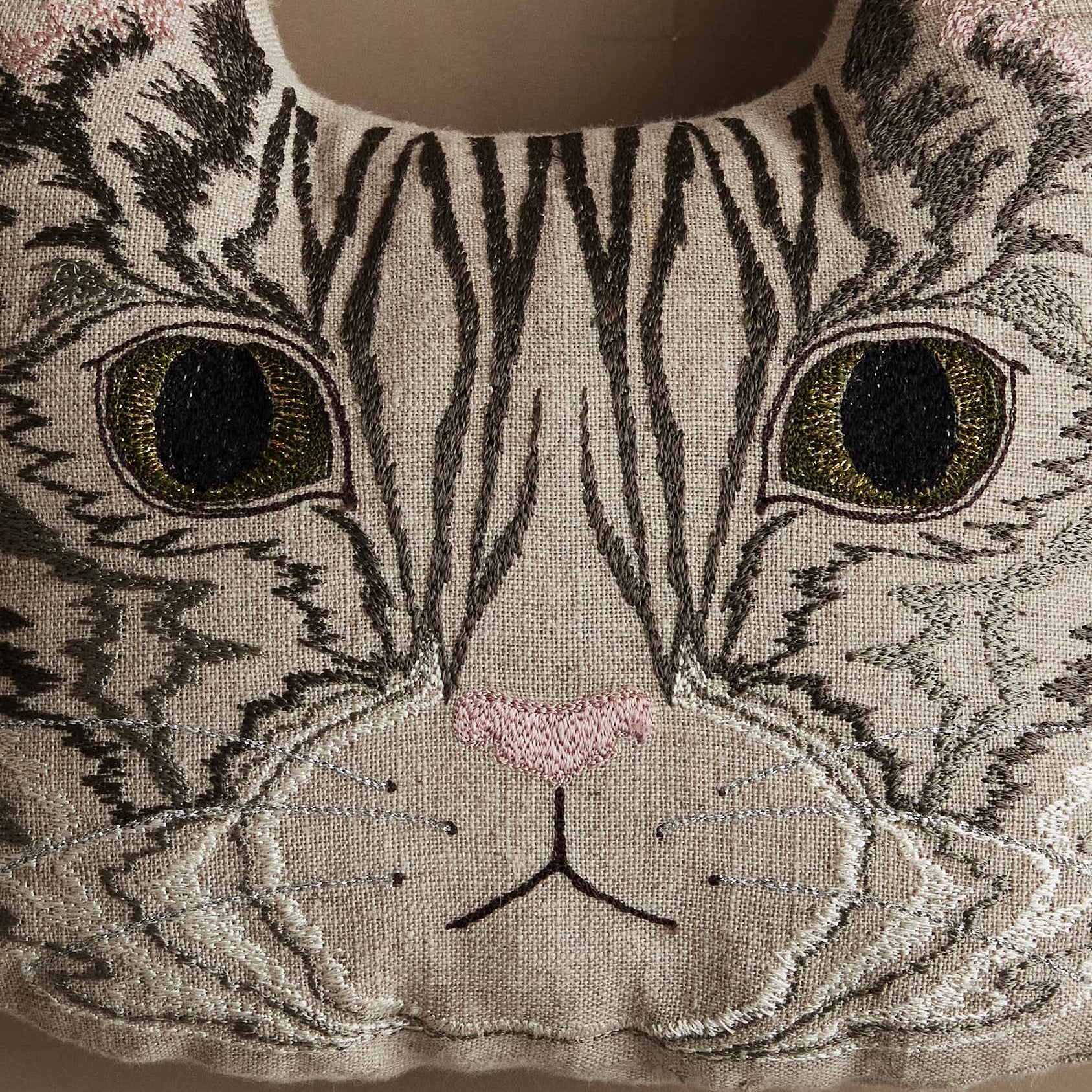 Embroidered cat face design on a fabric background