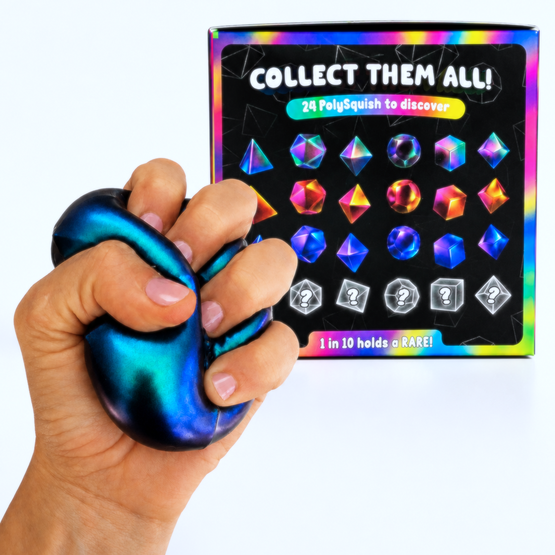 A hand squeezes a shiny iridescent blue stress ball in front of its colorful product box on a white background. The box reads 'COLLECT THEM ALL!' and shows holographic polyhedron graphics.