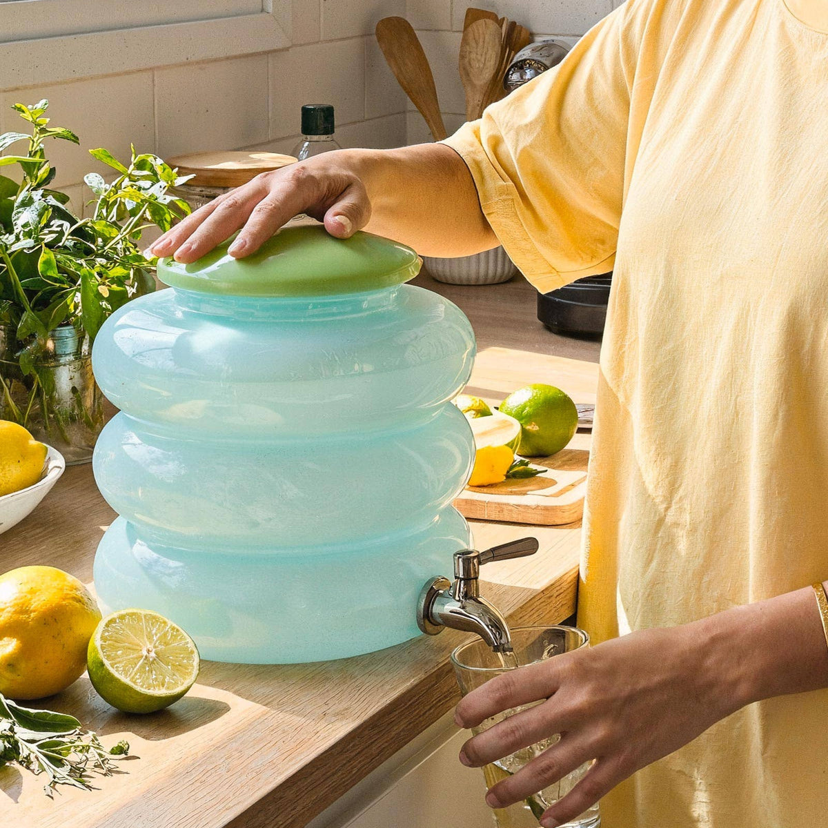 Person using a collapsible water container with a faucet in a kitchen.