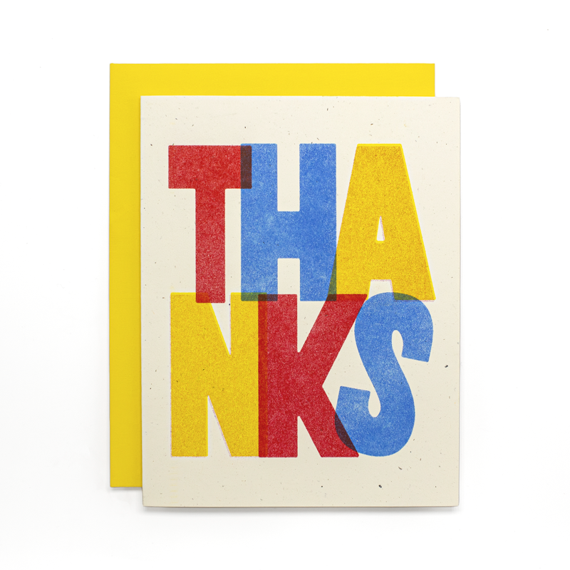 A square greeting card with a bright yellow envelope behind it. The card features the word 'THANKS' in large, bold, overlapping letters in red, yellow, and blue on a speckled off-white background.