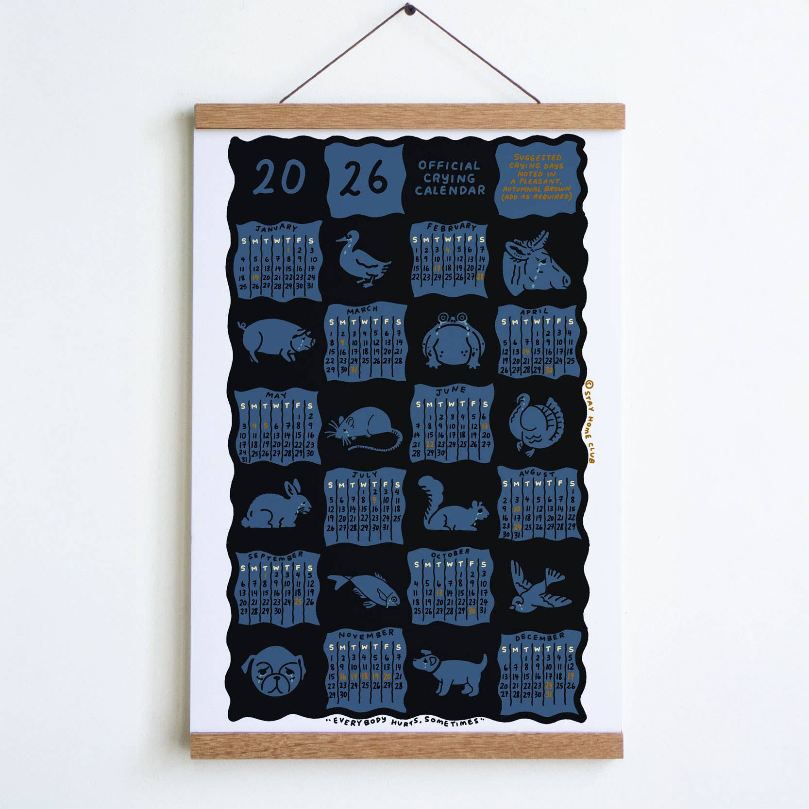 Calendar with blue animal illustrations on a black background, framed and hanging on a white wall.