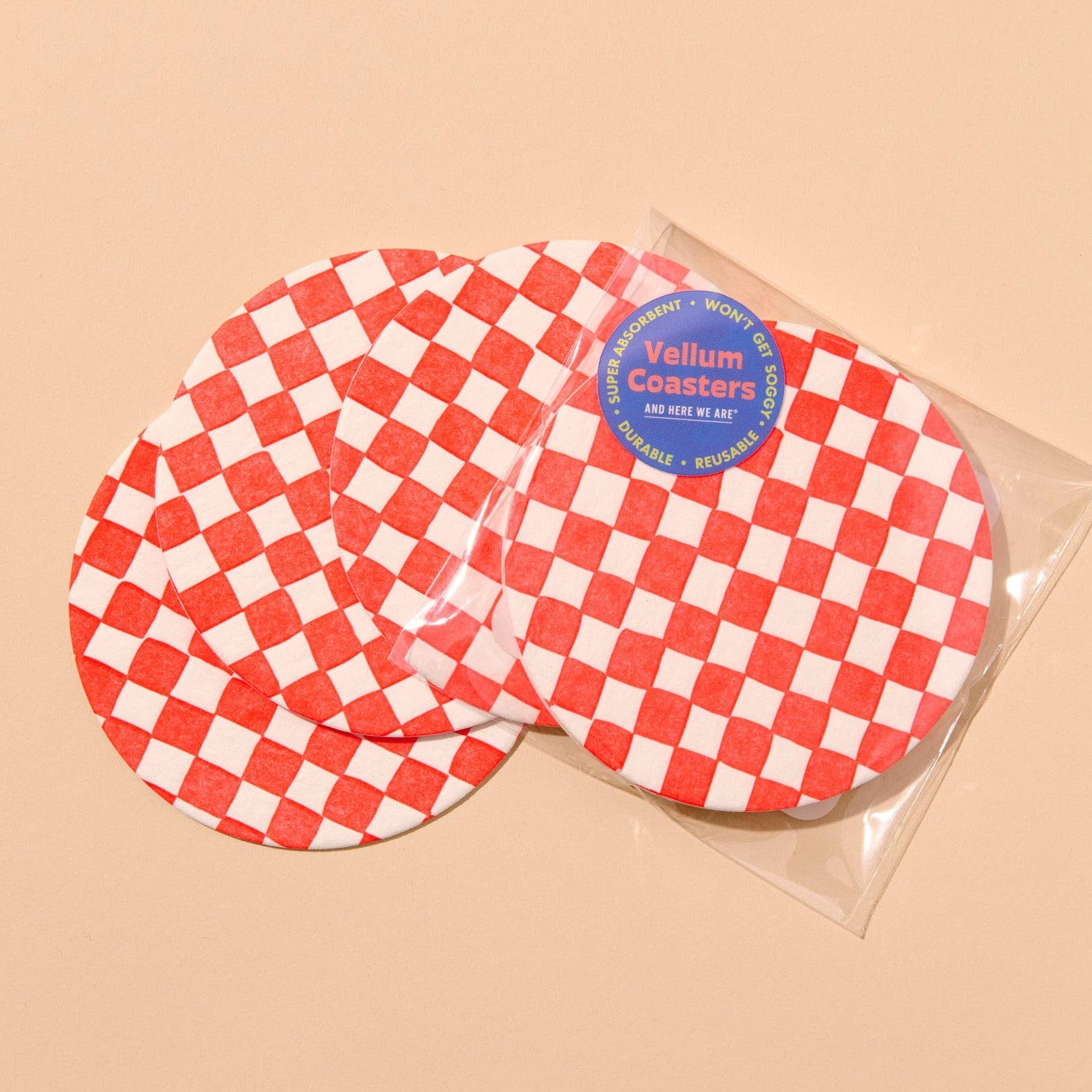 Red and white checkered coasters with a clear packaging sleeve on a beige background