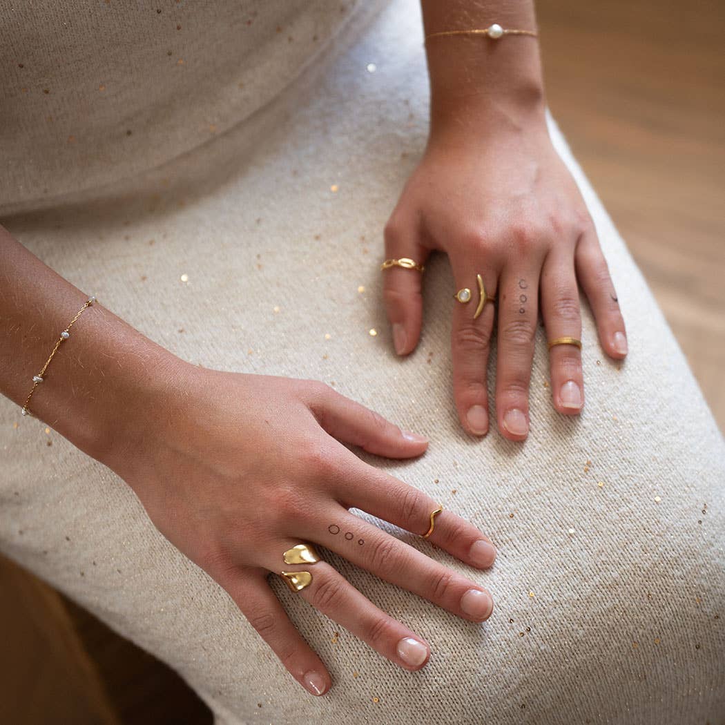 Close-up of two hands with gold rings on a textured surface