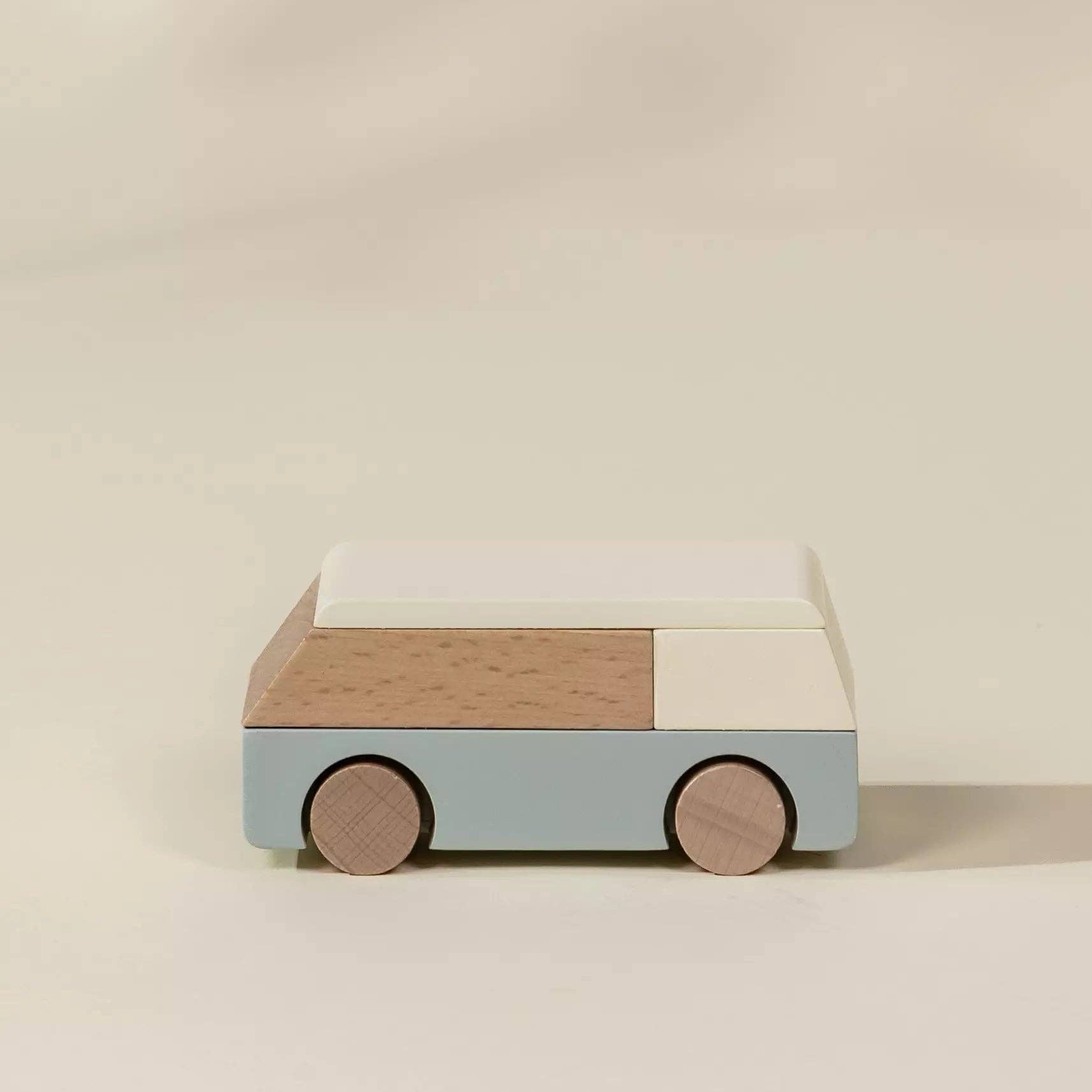 Wooden toy car with a light blue body and brown wheels on a beige background