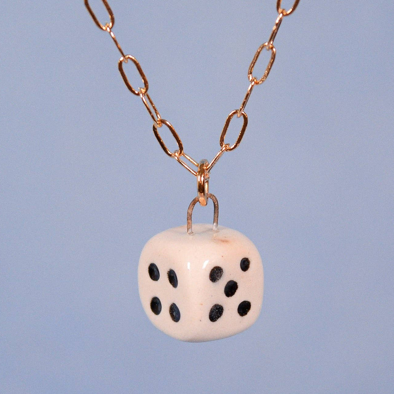 Necklace with a dice-shaped pendant on a blue background