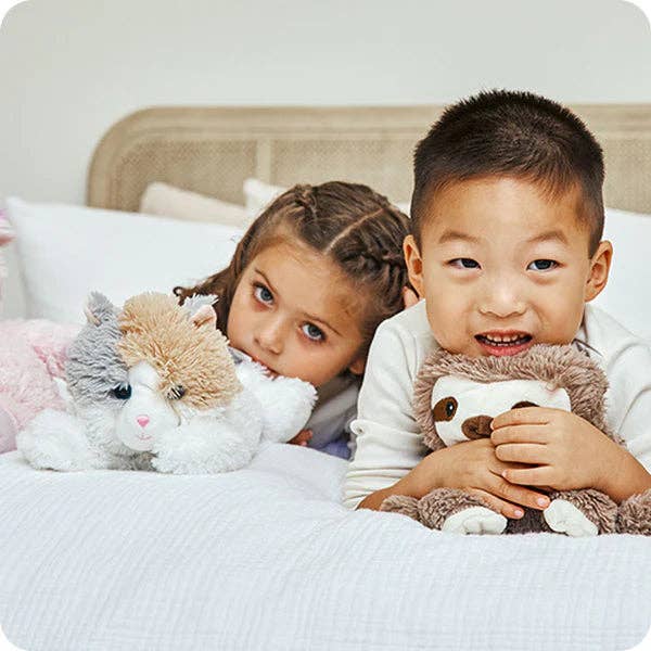 Two children with plush toys on a bed
