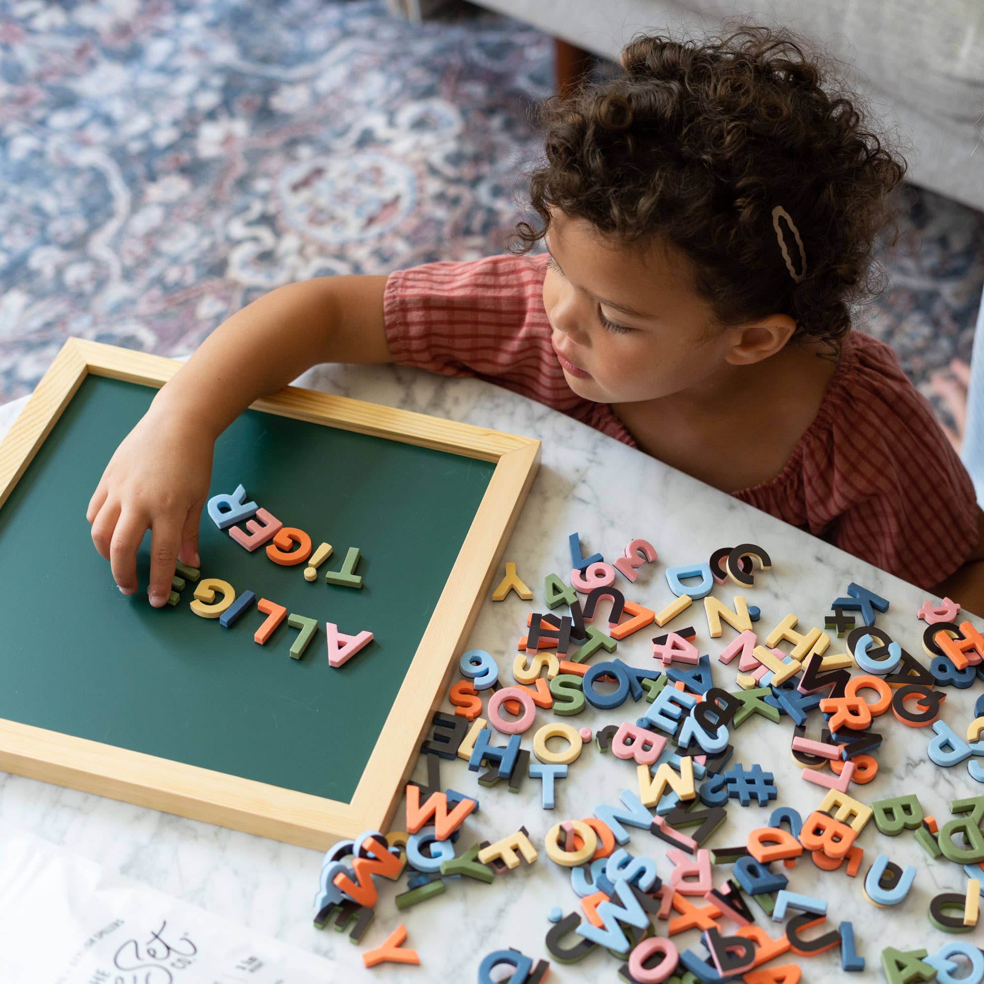 Child playing with colorful magnetic letters on a green board