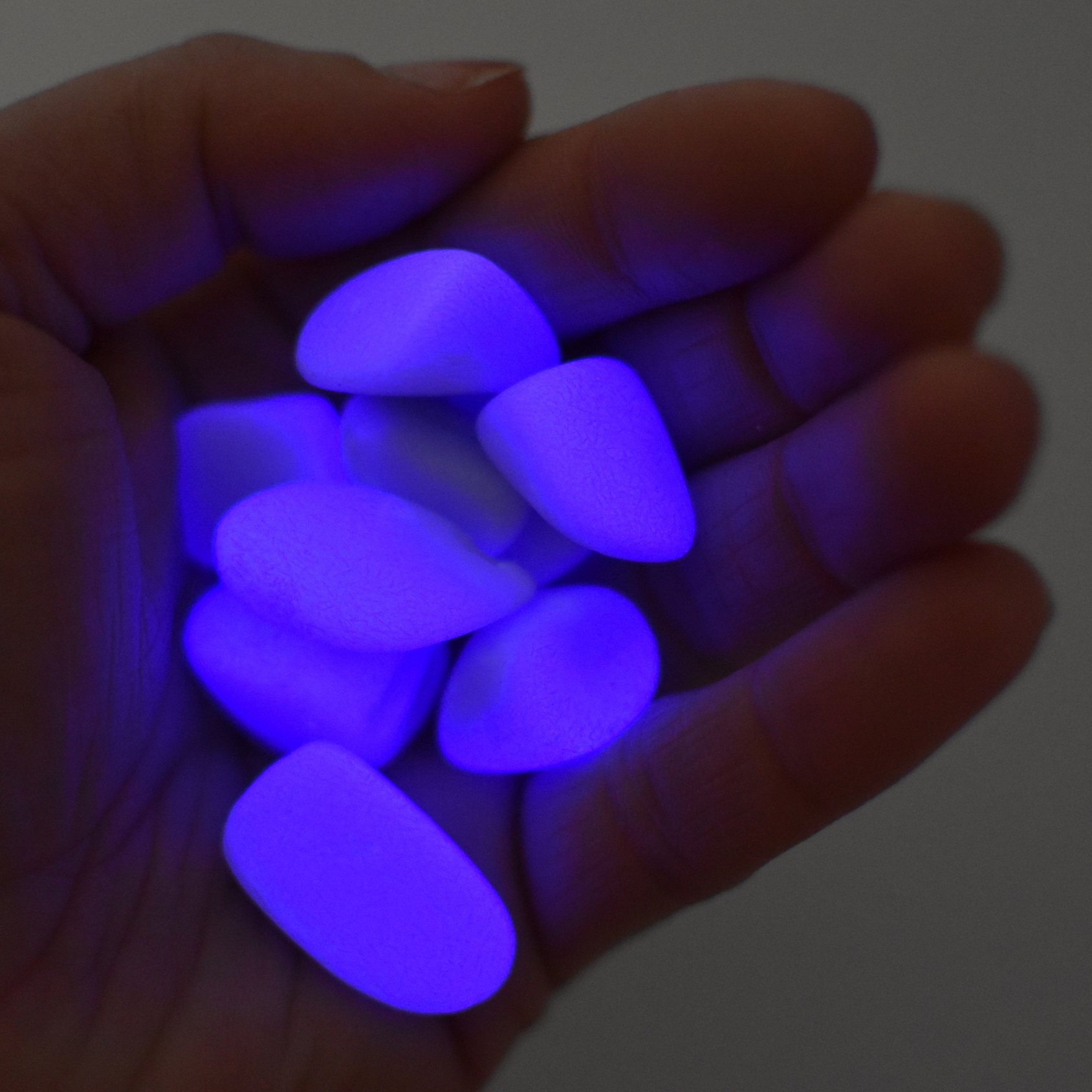 Hand holding purple glowing stones against a dark background