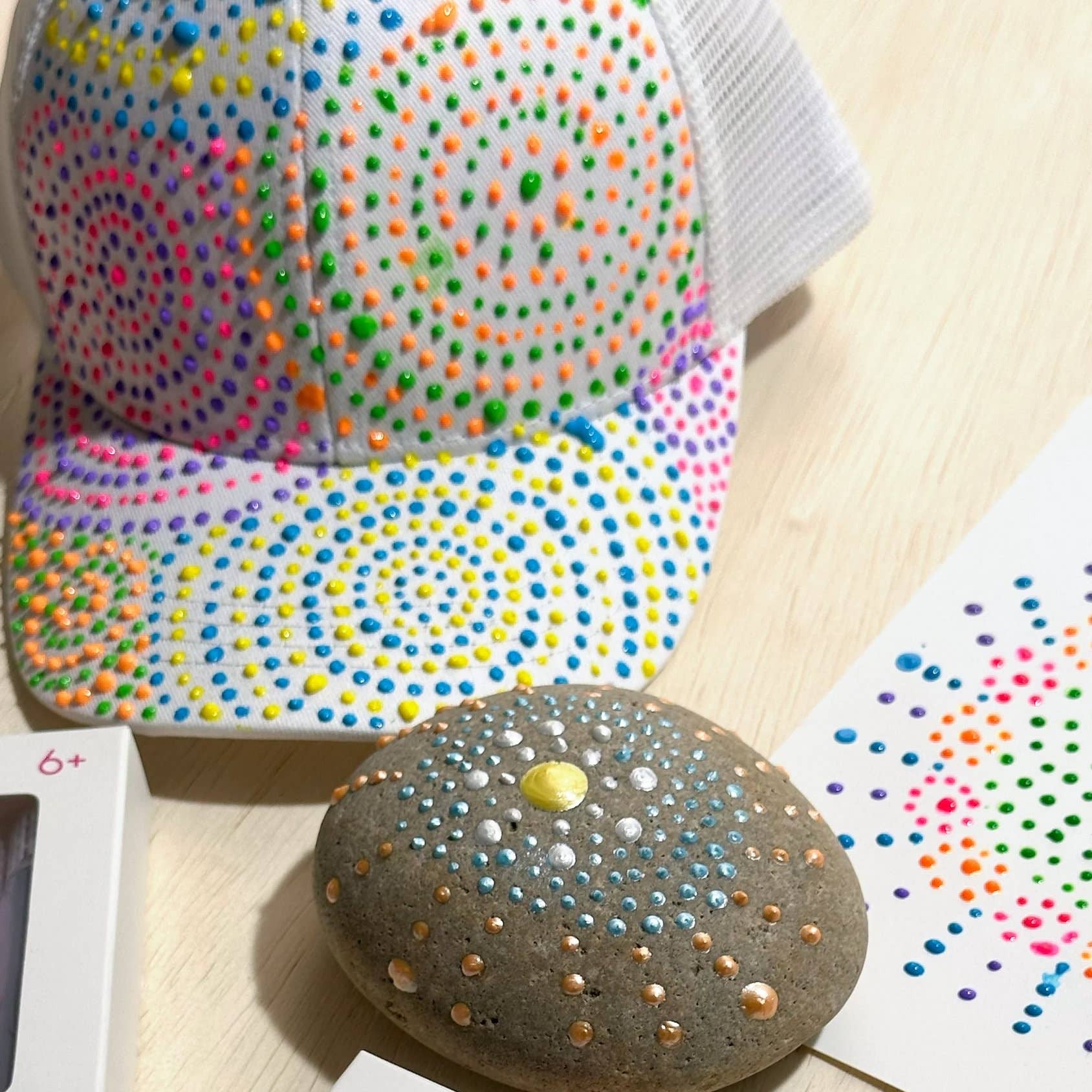 Colorful dot-a-box dimensional craft set with a rock and dot art on a wooden surface