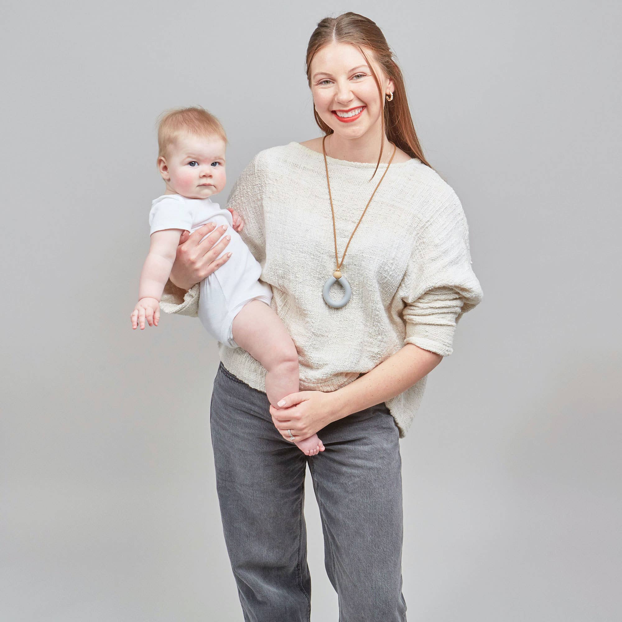 Woman holding a baby against a plain background