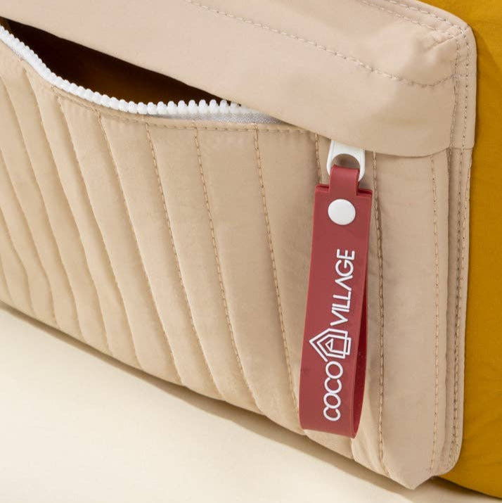 Close-up of a beige and mustard-colored bag with a red tag featuring 'Coco Village' branding.