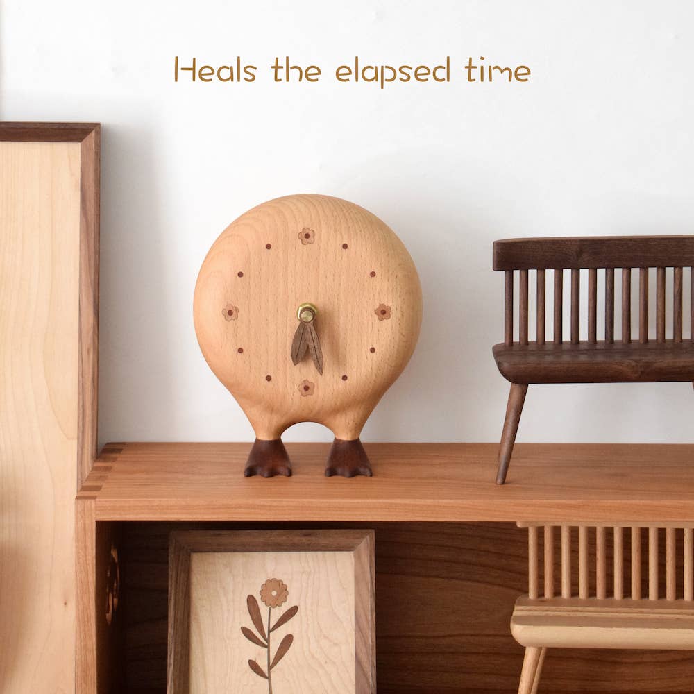 Wooden clock on a shelf with text 'Heals the elapsed time' above it.