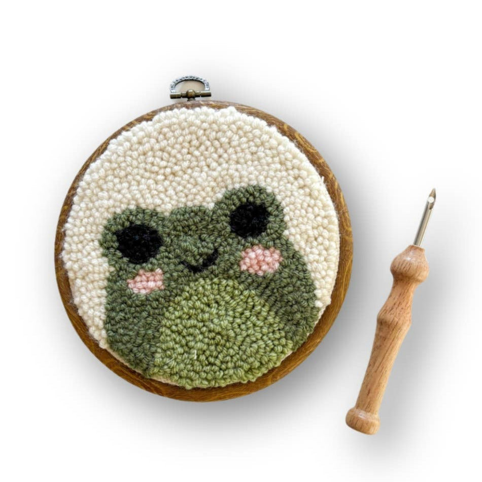 Embroidery hoop with a cute face design and a wooden crochet hook on a white background