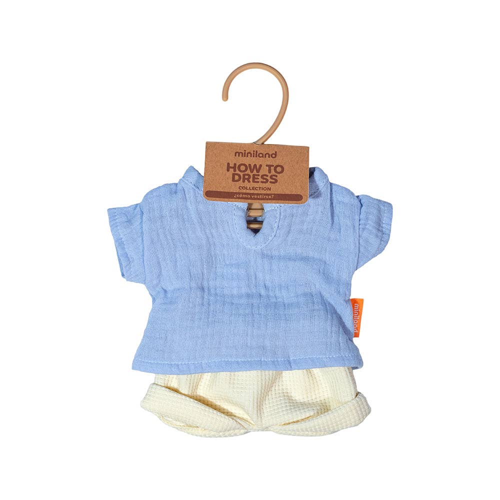 Blue doll's shirt and white shorts set on a hanger with 'miniland' tag.
