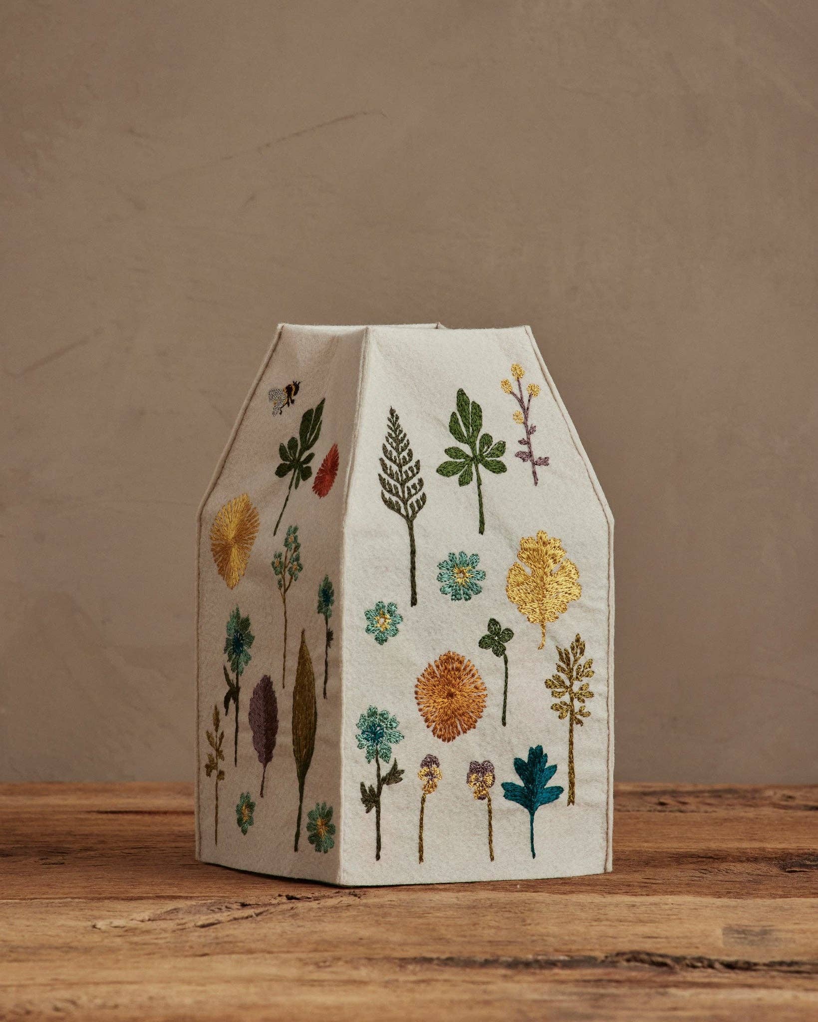Decorative paper house with floral patterns on a wooden surface and brown background