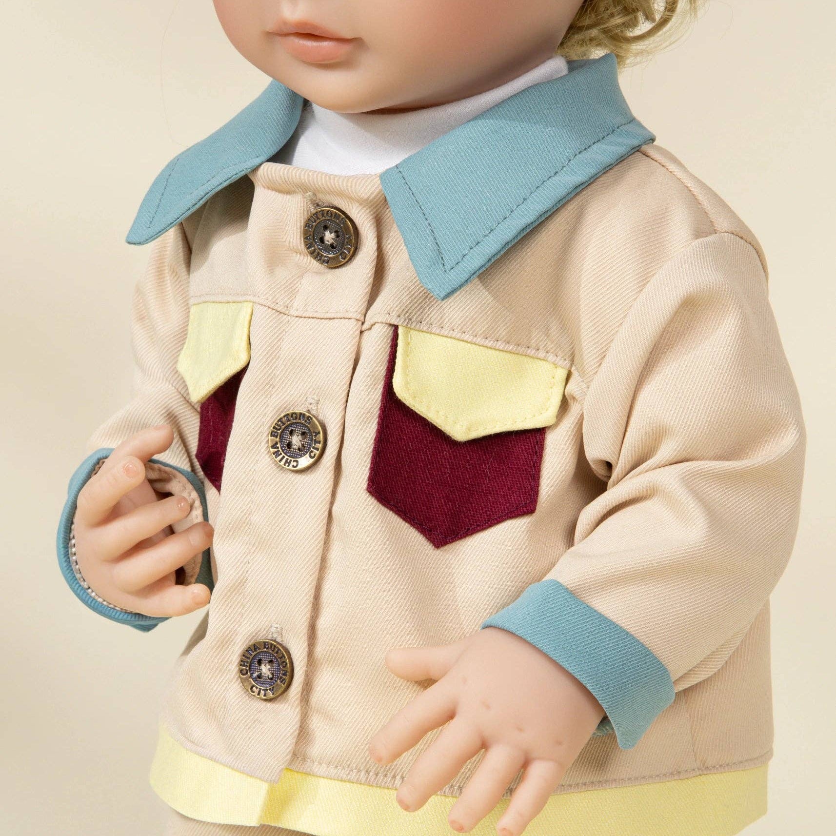 doll wearing a colorful jacket with a beige background