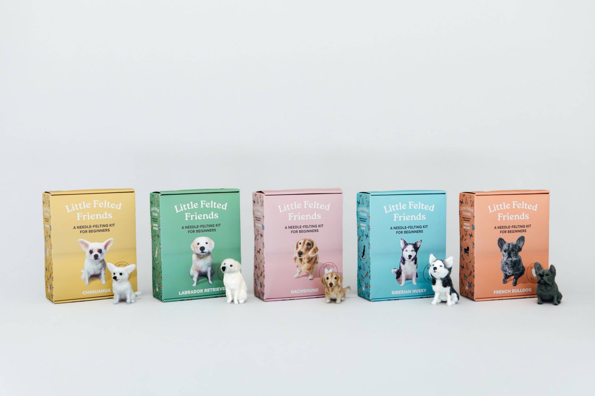 Five 'Little Peanut Friends' dog-themed boxes in different colors (yellow, green, pink, blue, and orange) are lined up on a white surface with small dog figurines placed in front of each box.