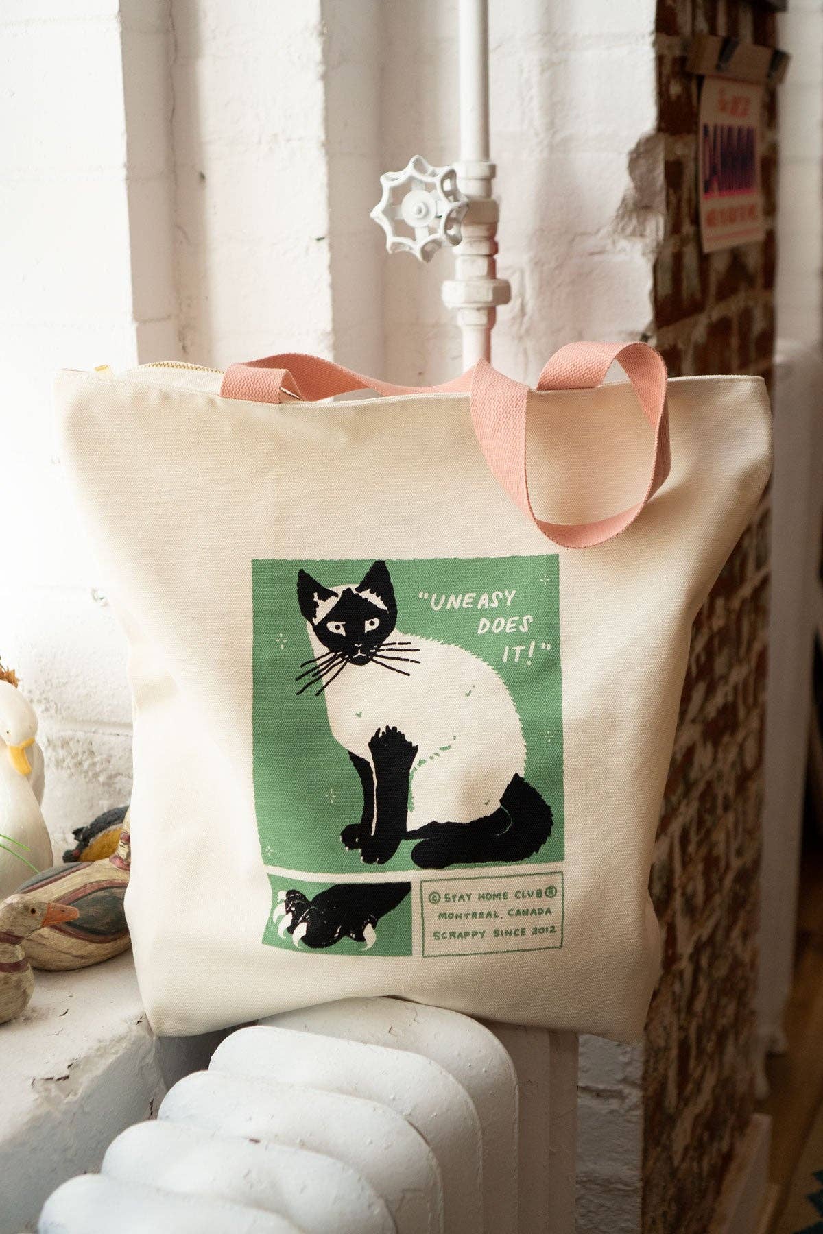 Tote bag with a cat illustration and text on a white surface