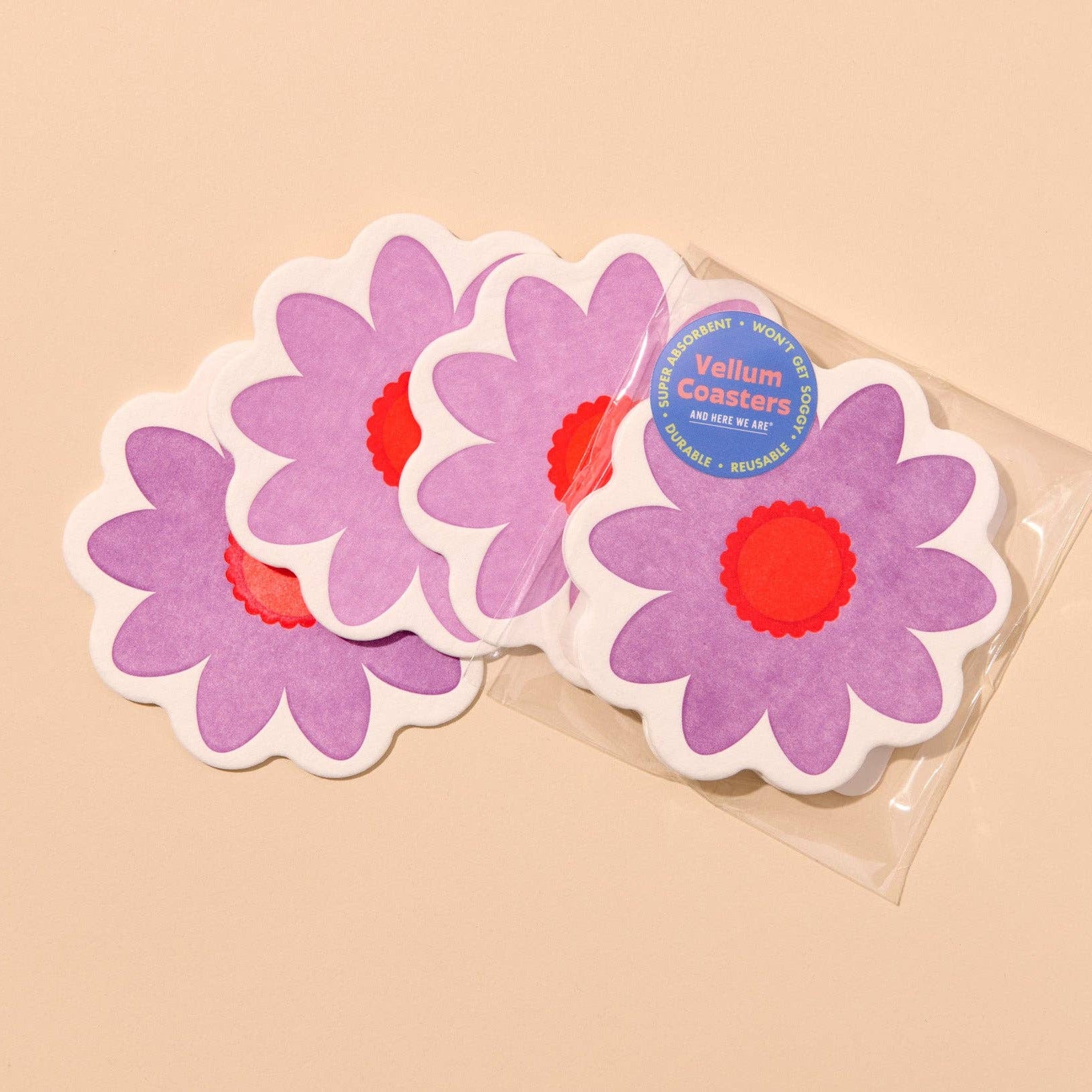 four purple flower-shaped coasters with red centers on a beige background