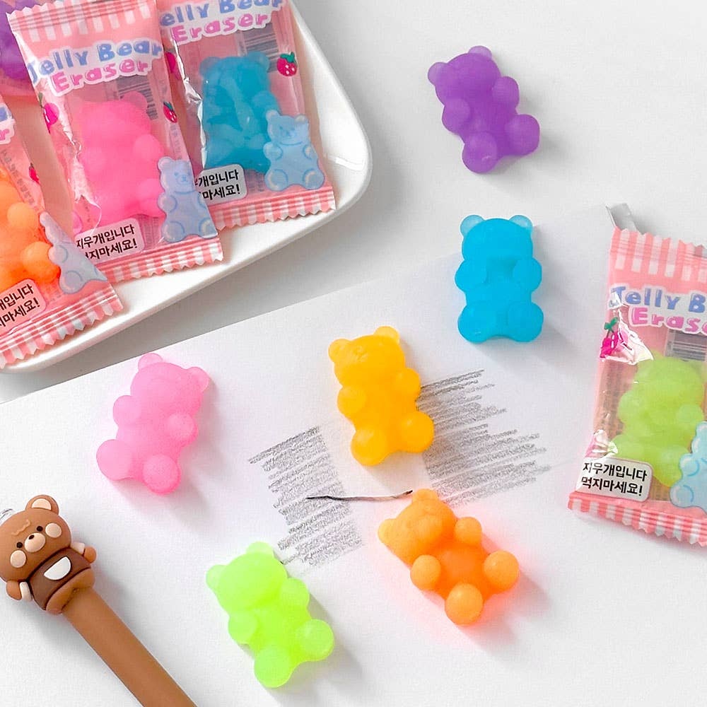 Colorful gummy bear-shaped erasers with packaging on a white surface